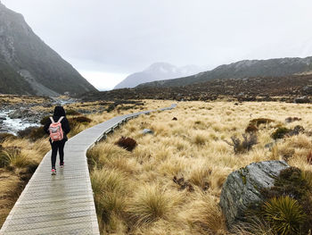 Rear view of woman walking on mountain against sky