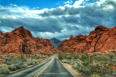 Road leading towards mountains against sky