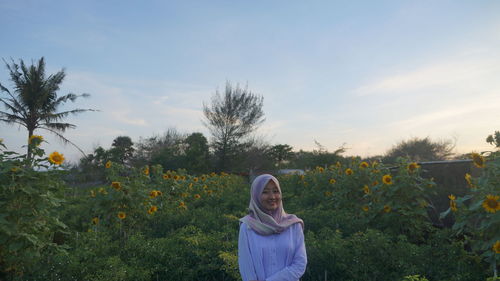 Woman standing by sunflower against sky