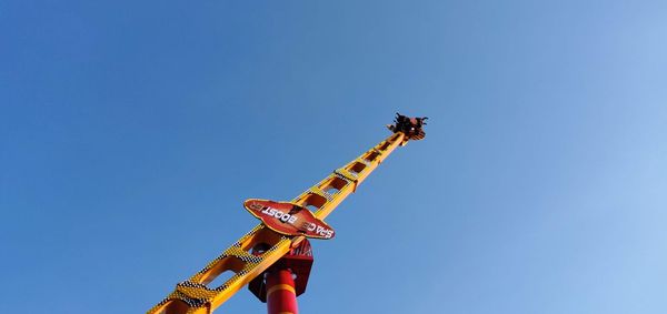 Low angle view of chain swing ride against clear blue sky