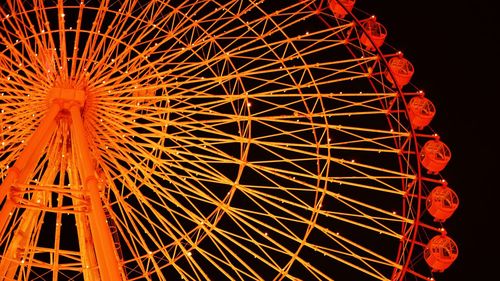 Low angle view of illuminated ferris wheel against sky at night