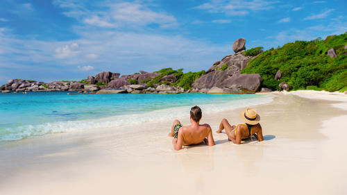 Rear view of people on beach against sky