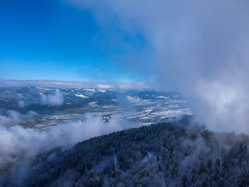 Aerial view of snow covered landscape against blue sky