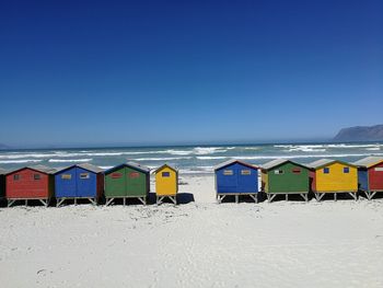 Lounge chairs on beach against clear blue sky