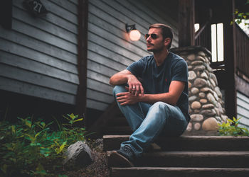 Full length of young man sitting in sunglasses