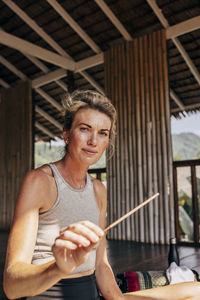 Portrait of woman holding incense stick at wellness resort