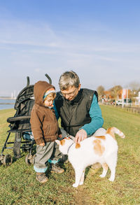 Grandfather and granddaughter with dog on land