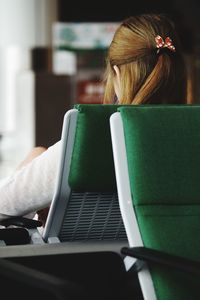 Rear view of woman using laptop at home