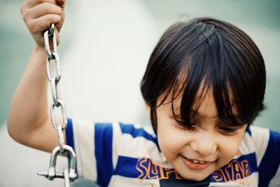 Close-up of smiling boy swinging in playground