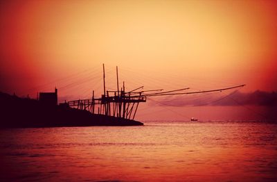 Silhouette ship in sea against sky during sunset