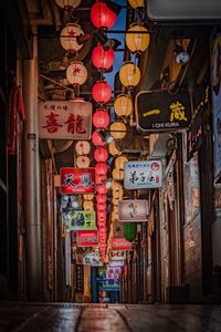 Illuminated lanterns hanging on alley amidst buildings