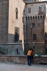 Rear view of woman standing by old building