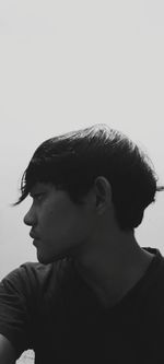 Portrait of young man looking away against white background