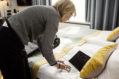 High angle view of businesswoman typing on laptop at hotel room