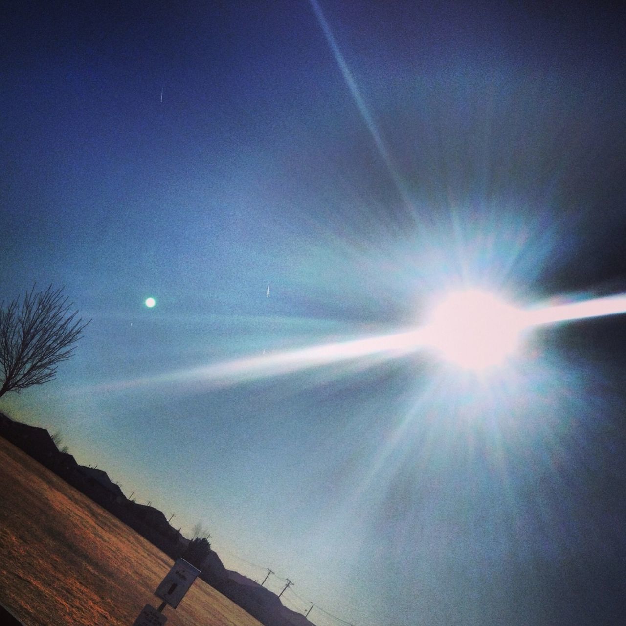 sun, low angle view, sunbeam, lens flare, sunlight, sky, built structure, architecture, building exterior, bright, blue, sunny, vapor trail, beauty in nature, nature, tree, silhouette, moon, outdoors, cloud - sky