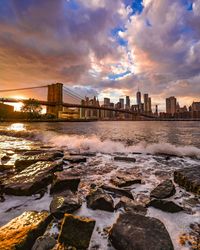 View of buildings by sea against sky during sunset
