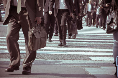 Low section of people walking on street in city