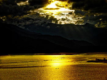 Scenic view of sea and mountains against dramatic sky