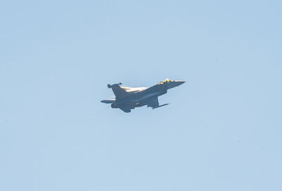 Low angle view of airplane flying against clear blue sky