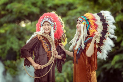 Young female friends wearing costumes against trees