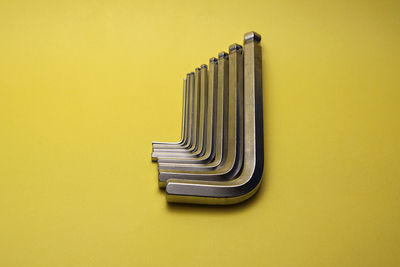 Directly above view of silver hex wrenches against yellow background