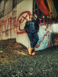 Full length of young woman against graffiti wall