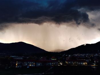 Illuminated cityscape against cloudy sky