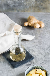 Bottle with natural ginger serum and chopped ginger in a bowl on the table. natural care cosmetics. 