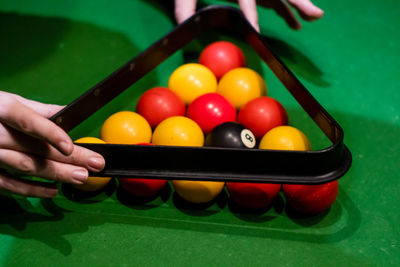 Cropped hands of woman holding pool balls on table