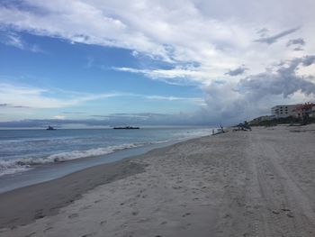 Scenic view of beach against cloudy sky