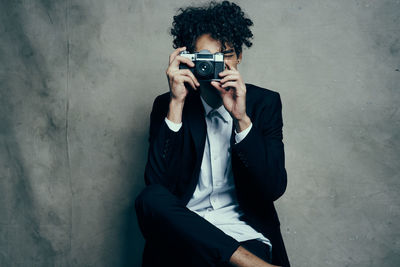 Young man using camera against wall
