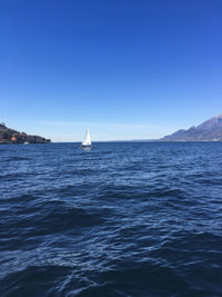 Sailboat sailing in sea against clear blue sky