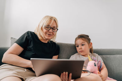 Woman with grandchild using tablet pc at home