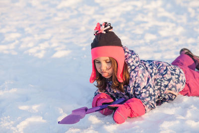 Girl lying on snow during winter