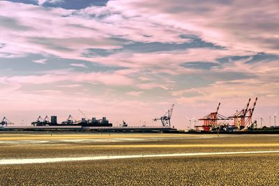 Commercial dock by road against cloudy sky