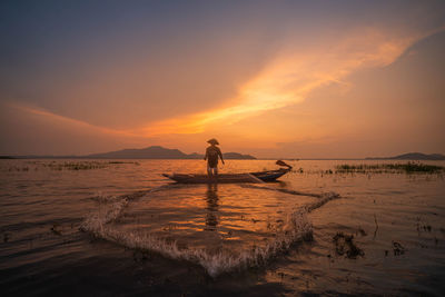 Silhouette man standing on beach against sky during sunset