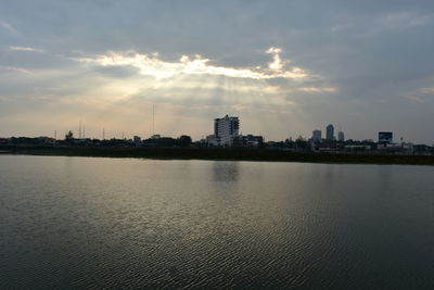 City at waterfront against cloudy sky