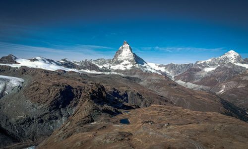 Scenic view of snowcapped mountains against blue sky