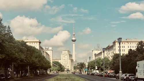 Street amidst buildings against cloudy sky