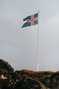 Low angle view of flag on rock against sky