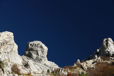 Low angle view of rocks against blue sky