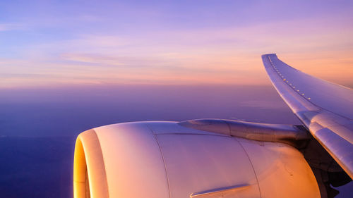 Airplane wing against sky during sunset