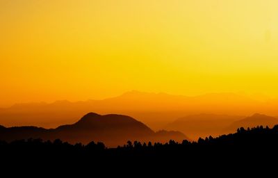 Scenic view of silhouette mountains against orange sky