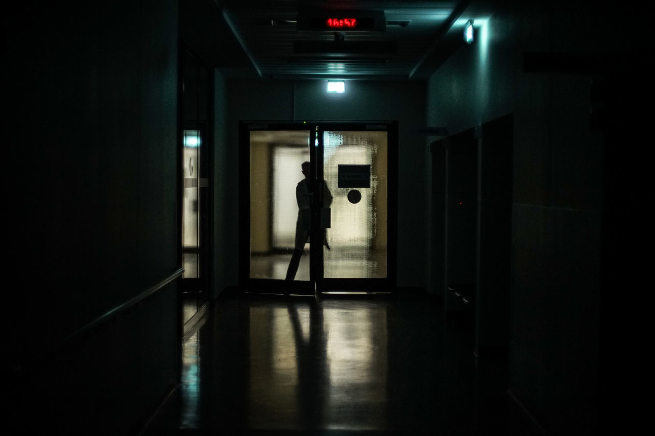 architecture, entrance, one person, real people, door, indoors, full length, standing, arcade, building, corridor, built structure, illuminated, men, dark, silhouette, lifestyles, walking, reflection, flooring
