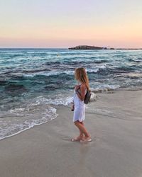 Full length of man standing on beach against sky during sunset