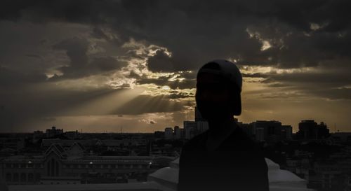 Portrait of silhouette man and buildings against sky during sunset