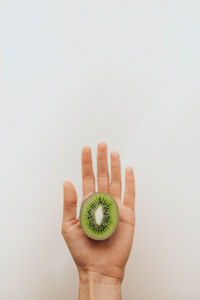 Cropped image of hand holding fruit against white background