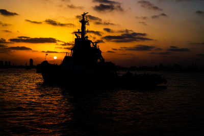 Silhouette of ship in sea during sunset