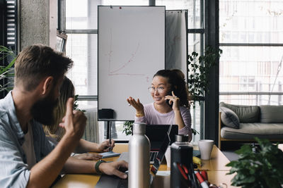 Smiling businesswoman discussing with male and female colleagues in office