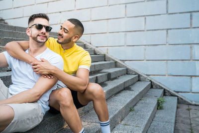 Gay men embracing while sitting on staircase